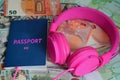 The biometric passport and pink headphones lie on the background of Euro and dollar paper money. expensive vacation, necessary Royalty Free Stock Photo