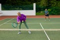 Biracial active senior woman with senior man playing tennis in tennis court against trees Royalty Free Stock Photo