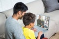 Biracial boy with father using laptop for video call, with diverse high school pupils on screen Royalty Free Stock Photo