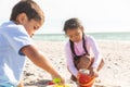 Biracial boy and girl playing while making sandcastle with toys at beach on sunny day Royalty Free Stock Photo