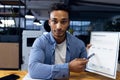 Biracial businessman sitting holding documents and making video call, working late at office Royalty Free Stock Photo