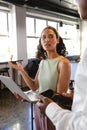 Biracial businesswoman discussing strategy with businessman over laptop in creative office Royalty Free Stock Photo