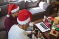 Biracial father and adult son making laptop christmas video call with waving couple Royalty Free Stock Photo