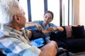 Biracial female doctor examining caucasian senior man's blood pressure with gauge at home