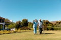 Biracial female doctor pointing while assisting caucasian senior man in walking with walker in yard Royalty Free Stock Photo