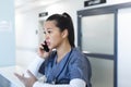 Biracial female doctor talking on smartphone at reception desk in hospital Royalty Free Stock Photo