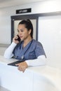 Biracial female doctor talking on smartphone at reception desk in hospital Royalty Free Stock Photo