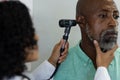 Biracial female doctor using otoscopy and examinating african american male patient