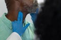 Biracial female doctor wearing medical gloves examinating african american male patient