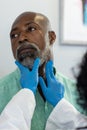 Biracial female doctor wearing medical gloves examinating african american male patient