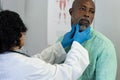 Biracial female doctor wearing medical gloves examinating african american male patient