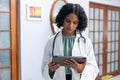 Biracial female doctor wearing sthethoscope, using tablet at doctor\'s office Royalty Free Stock Photo