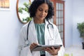 Biracial female doctor wearing sthethoscope, using tablet at doctor's office Royalty Free Stock Photo