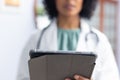 Biracial female doctor wearing sthethoscope, using tablet at doctor\'s office Royalty Free Stock Photo