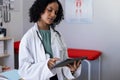 Biracial female doctor wearing sthethoscope, using tablet at doctor's office Royalty Free Stock Photo