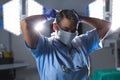 Biracial female surgeon wearing scrubs and face mask in operating theatre Royalty Free Stock Photo