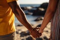 Biracial gay couples hands embrace on a sunlit beach together