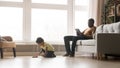 Black father use laptop little son play cars at home Royalty Free Stock Photo