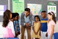 Biracial male teacher using tablet teaching children in elementary school class Royalty Free Stock Photo