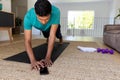 Biracial man exercising and using smartphone at home, copy space Royalty Free Stock Photo