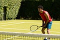 Biracial man with racket waiting for ball to return on sunny outdoor tennis court, copy space Royalty Free Stock Photo