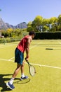 Biracial man with tennis racket bouncing ball to serve on sunny outdoor tennis court, copy space Royalty Free Stock Photo