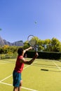 Biracial man with tennis racket returning ball to player on sunny outdoor tennis court, copy space Royalty Free Stock Photo