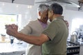 Biracial senior couple with head to head holding hands and dancing in kitchen Royalty Free Stock Photo