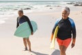 Biracial senior couple with surfboards walking at beach during sunny day Royalty Free Stock Photo