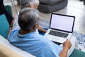 Biracial senior couple using laptop while relaxing on sofa in living room, copy space Royalty Free Stock Photo