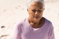 Biracial senior woman meditating with eyes closed at beach on sunny day Royalty Free Stock Photo