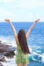 Biracial teen girl arms raised by ocean water in praise