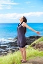 Biracial teen girl on cliff, arms outstretched by ocean