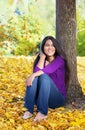 Biracial teen girl leaning against tree, autumn leaves on groun Royalty Free Stock Photo