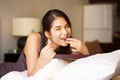 Biracial teen girl lying on bed eating chocolates, smiling