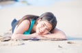 Biracial teen girl lying on sandy beach, resting and smiling Royalty Free Stock Photo