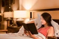 Biracial teen girl reading book in bed at night Royalty Free Stock Photo