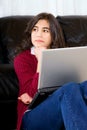 Biracial teen girl sitting against couch with laptop