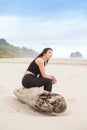 Biracial teen girl sitting on log quietly looking at ocean Royalty Free Stock Photo