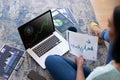 Biracial woman sitting on floor using laptop with statistical data on screen Royalty Free Stock Photo