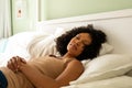 Biracial woman taking nap on bed in bedroom Royalty Free Stock Photo