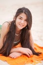 Biracial yeen girl lying on orange blanket at beach Royalty Free Stock Photo