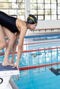 Biracial young female swimmer preparing to dive into an indoor pool, wearing a black swimsuit Royalty Free Stock Photo