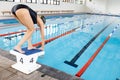 Biracial young female swimmer preparing to dive into indoor swimming pool, copy space