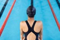 Biracial young female swimmer standing at pool edge indoors, preparing to dive