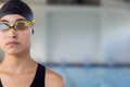 Biracial young female swimmer standing by pool indoors, wearing goggles, copy space Royalty Free Stock Photo