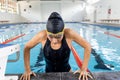 A biracial young female swimmer, wearing goggles, resting at swimming pool edge Royalty Free Stock Photo