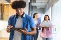 Biracial young man holding tablet in a modern business office, two women behind using tech Royalty Free Stock Photo