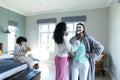 Biracial young woman applying beauty cream on smiling friend's face and female sitting on bed Royalty Free Stock Photo