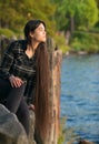 Biracial young woman sitting  looking out over lake at sunset Royalty Free Stock Photo